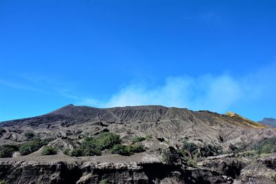 Scenic view of volcanic mountain against blue sky