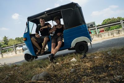 Portrait of friends sitting on jinrikisha on road