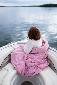 Rear view of girl sitting on boat sailing in sea