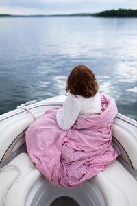 Rear view of person sitting on boat in sea