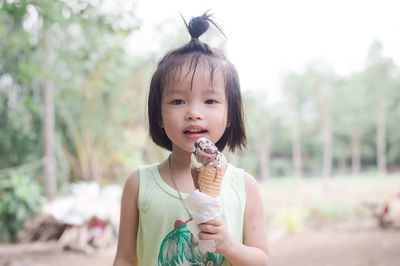 Portrait of cute girl eating ice cream while standing outdoors