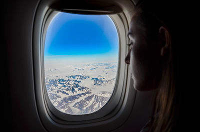 Reflection of clouds in sky seen through airplane window