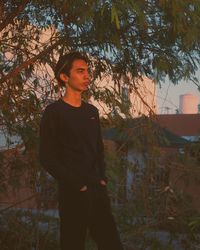 Young man standing against trees