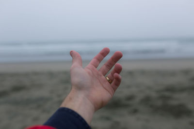 Close-up of hand against sea