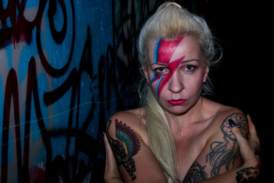 Portrait of topless woman with face paint at night