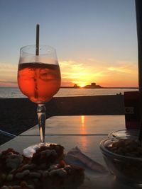 Red wine in glass on table against sea during sunset