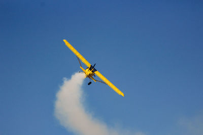 Low angle view of airplane flying against blue sky