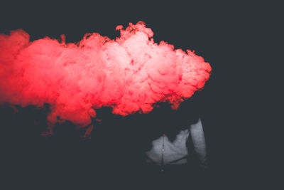 Smoke by man standing against black background