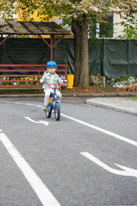 Rear view of man riding push scooter on road