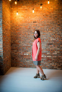 Full length of woman standing against illuminated wall