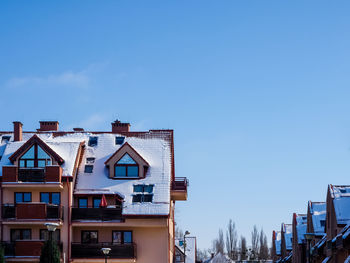 Tenements building roof covered with snow on a blue sky background