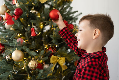Side view of young woman holding christmas tree