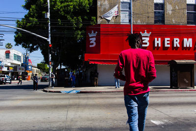 Rear view of man walking on footpath in city