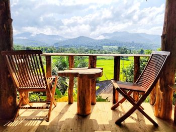 Empty chairs and tables against sky