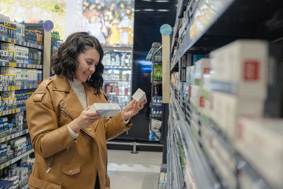 Young woman drinking wine in supermarket