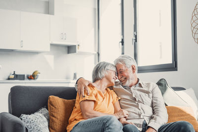 Side view of woman sitting on sofa at home