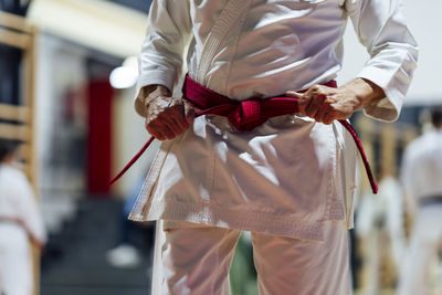 Active senior man tightening belt while practicing karate in class