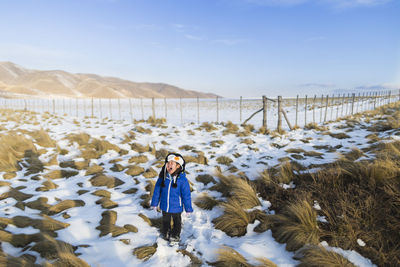 Full length of girl screaming while standing on snow covered field during winter