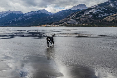 Scenic view of lake by snowcapped mountains against sky with a dog at jasper national park 