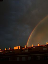 Low angle view of rainbow over buildings against sky
