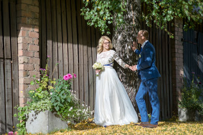 Smiling bridal couple looking at each other while standing by barn