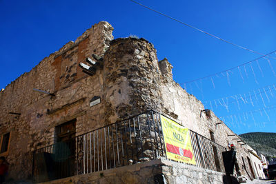 Low angle view of abandoned building against clear blue sky