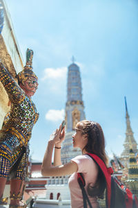 Woman photographing statue in city