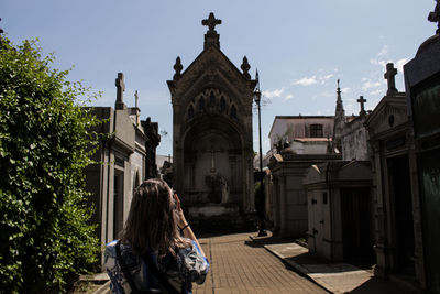 Rear view of woman walking in building against sky