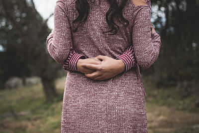 Cropped hands of man embracing woman while standing on grass