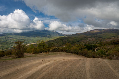 Scenic view of road by mountains against sky