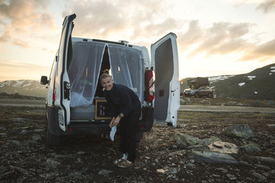 Smiling woman standing in front of camper van