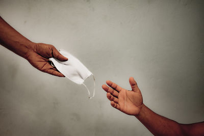 Close-up of hands holding white wall against gray background