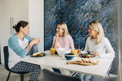 Three women chatting and having dinner at home. friends met, smiling and relaxing while talking.