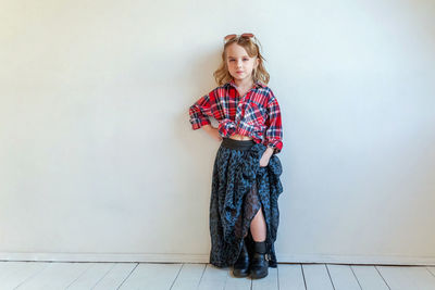 Portrait of young woman standing against wall