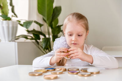 A girl student sits at a desk in the classroom and collects figures / puzzles / small toys 