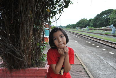Portrait of girl sitting on railroad station platform