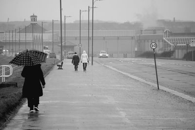 Rear view of people walking on street during rainy season