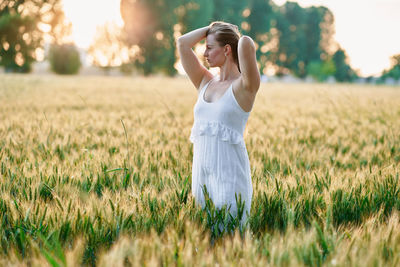 Young girl with long hair standing in a field at a sunny summer day in late afternoon