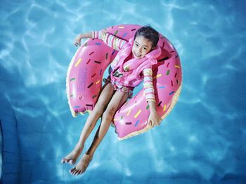 High angle portrait of cute girl in inflatable ring floating on swimming pool