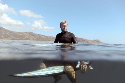 Portrait of happy man posing on surfboard in the sea