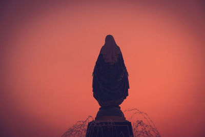 Statue against orange sky