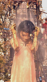 Midsection of woman standing by statue against trees