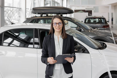 Portrait of young businesswoman standing in car