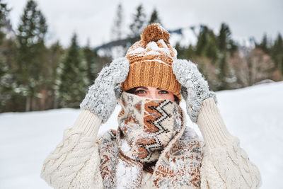 Portrait of woman wearing hat against trees during winter