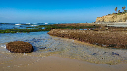 Rocks on beach against clear blue sky