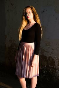 Portrait of young woman standing against wall