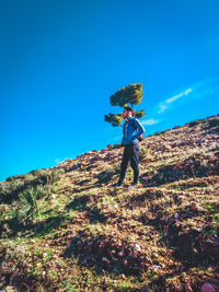 Full length of man standing on mountain against blue sky