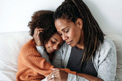 Smiling woman embracing daughter on sofa at home