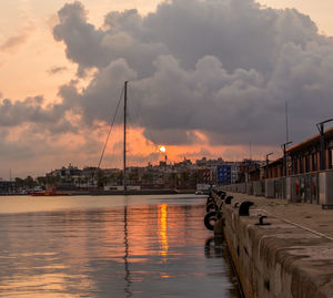 Scenic view of river by buildings against sky during sunset