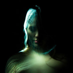 Close-up of woman against black background